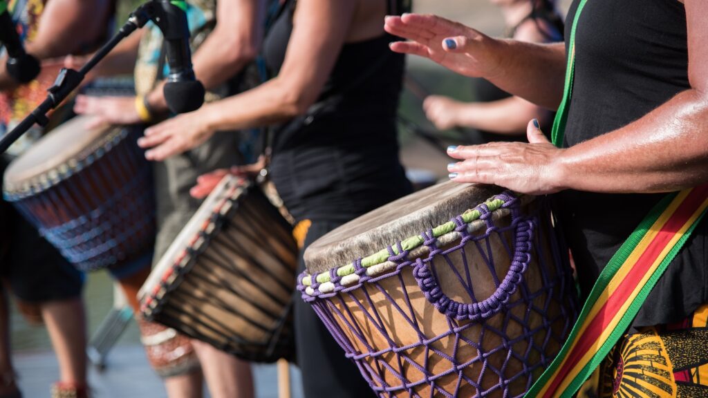 people playing goblet drums during daytime